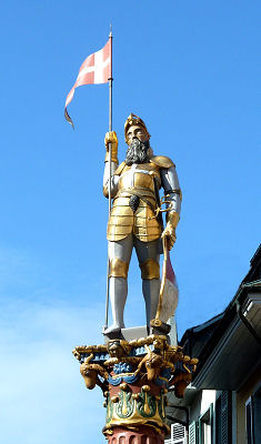 Der Bannerträger oder Venner (die zweitmächtigste Amtsperson nach dem Schultheiss) krönt die Säule des St. Ursen Brunnens mitten am Marktplatz